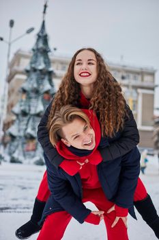 young family guy and girl spend the day in the park on a snowy day. Emotional young couple having fun while walking in the winter city, a lively man hugs his laughing beautiful woman