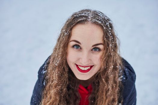 a young happy woman is having fun in a winter park, throwing snow, it is cold in her hands, the emissions are off scale