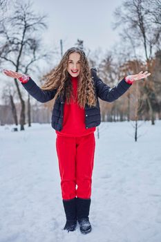 a young happy woman is having fun in a winter park, throwing snow, it is cold in her hands, the emissions are off scale