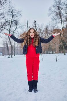 a young happy woman is having fun in a winter park, throwing snow, it is cold in her hands, the emissions are off scale