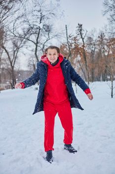 a young happy man is having fun in a winter park, throwing snow, it is cold in his hands, the emissions are off scale