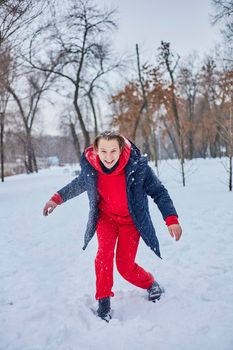 a young happy man is having fun in a winter park, throwing snow, it is cold in his hands, the emissions are off scale