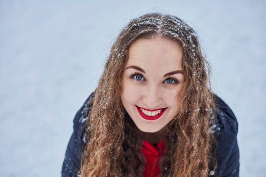 a young happy woman is having fun in a winter park, throwing snow, it is cold in her hands, the emissions are off scale