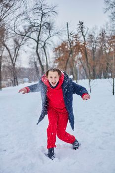 a young happy man is having fun in a winter park, throwing snow, it is cold in his hands, the emissions are off scale