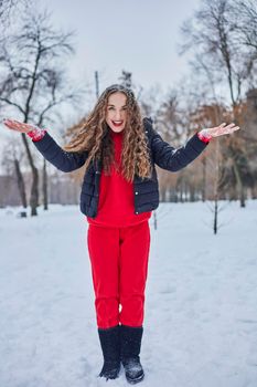 a young happy woman is having fun in a winter park, throwing snow, it is cold in her hands, the emissions are off scale