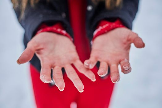 hands of a young woman, close-up, frozen from playing snowballs
