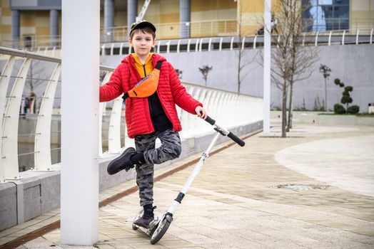 Happy family lifestyle and holiday concept. One little boy riding scooter, walking in city, street. Having fun alone.