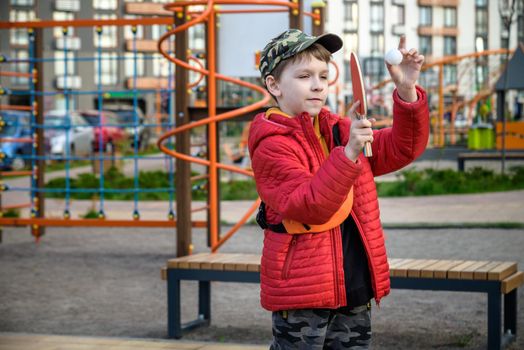 Caucasian boy exercise playing table tennis outdoors. Active leisure for children concept.