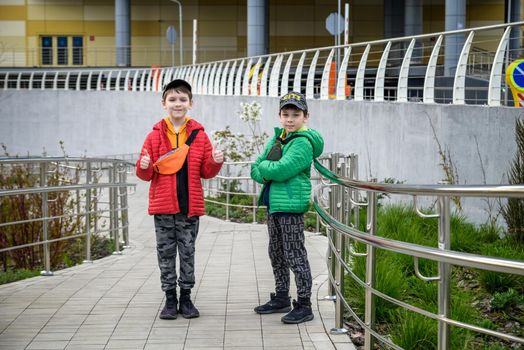 The friendship and communication of two teenage boys is 9, 11 years old, city street background.