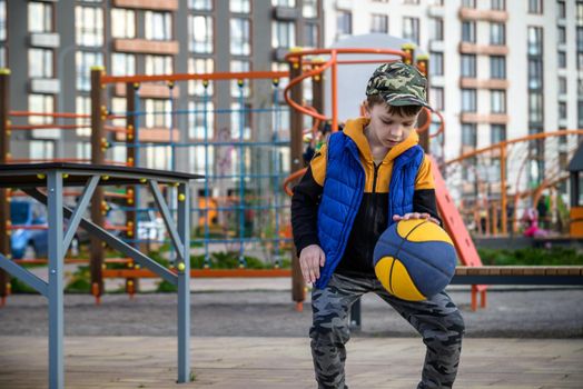 Portrait of a boy with a basketball on a basketball court. The concept of a sports lifestyle, training, sport, leisure, vacation.