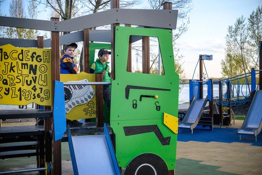Portrait of cute boys playing on slide at playground on sunny morning.