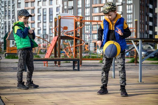 Two young friends playing basketball on court outdoors and having fun. Streetball players having a basketball game.