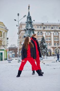 young family guy and girl spend the day in the park on a snowy day. Emotional young couple having fun while walking in the winter city, a lively man hugs his laughing beautiful woman