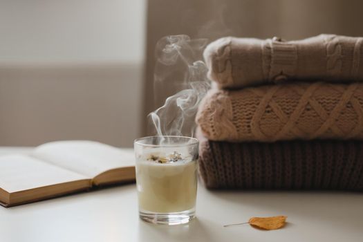cozy home atmosphere and still life with candle and sweaters on a table.