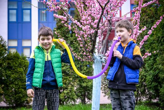 Colorful anti-stress fidget push pop tube toys for children. Flexible corrugated pipe in kids hands. Two Boys playing with sensory toys. Fun playing for developing imagination and fine motor skills.