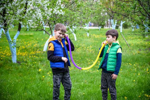 Colorful anti-stress fidget push pop tube toys for children. Flexible corrugated pipe in kids hands. Two Boys playing with sensory toys. Fun playing for developing imagination and fine motor skills.