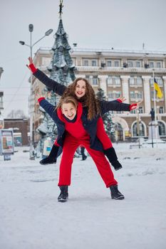 young family guy and girl spend the day in the park on a snowy day. Emotional young couple having fun while walking in the winter city, a lively man hugs his laughing beautiful woman