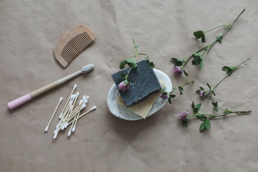 Soap bar or solid shampoo on a soap dish, bamboo toothbrush and towel top view with copyspace. Accessories for personal hygiene. Plastic free and eco friendly products in household.