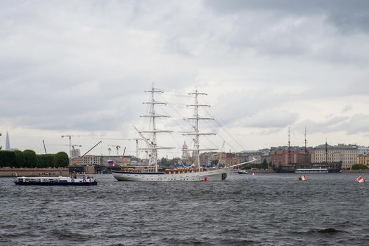 Saint-Petersburg, Russia. - July 27, 2002 View of city across the Neva water area with recreational water transport and sailing training vessel on roads on cloudy rainy summer evening. Selective focus