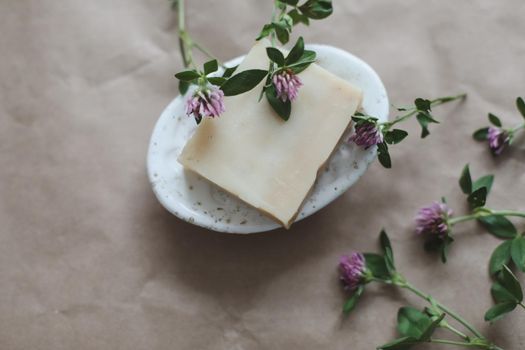 Handmade natural organic soap with flowers and pink towel on craft paper background top view with copyspace