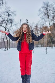 a young happy woman is having fun in a winter park, throwing snow, it is cold in her hands, the emissions are off scale