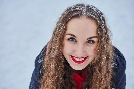 a young happy woman is having fun in a winter park, throwing snow, it is cold in her hands, the emissions are off scale