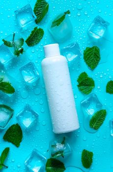 Bottle with cosmetics on a mint background with ice cubes. Selective focus. Spa.
