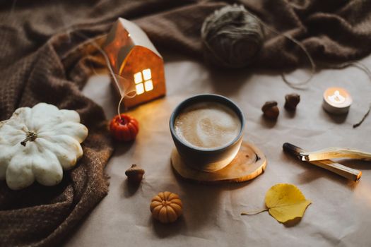 Autumn still life details in cozy home interior with a cup, candles, plaid. Hygge home decor. Halloween and Thanksgiving concept. Autumn banner