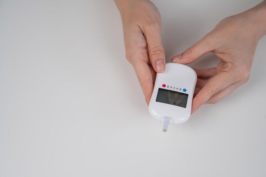 Woman measures blood sugar level with a glucometer