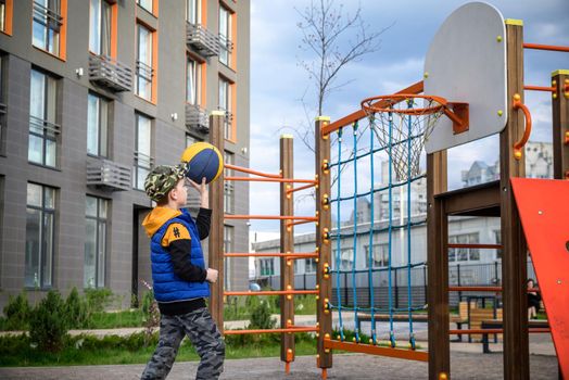 Portrait of a boy with a basketball on a basketball court. The concept of a sports lifestyle, training, sport, leisure, vacation.