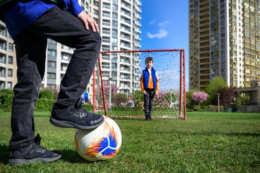 Little preschool boys friends playing soccer football on playground grass field outside. Happy authentic candid childhood lifestyle. Seasonal summer outdoor activity with ball for kids.