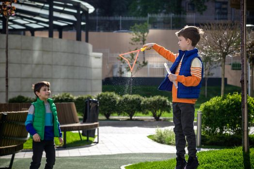 Two children blowing a soap bubbles. Boys playing. Kid blowing bubbles on nature. Friends at sunset, the sun's rays.