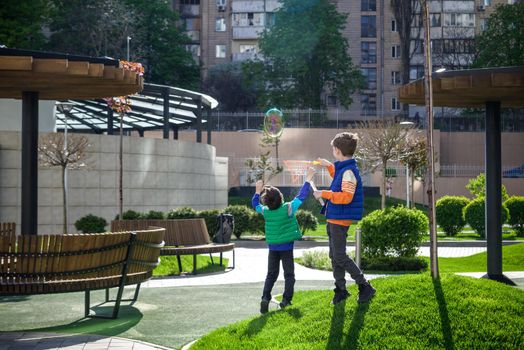 Two children blowing a soap bubbles. Boys playing. Kid blowing bubbles on nature. Friends at sunset, the sun's rays.