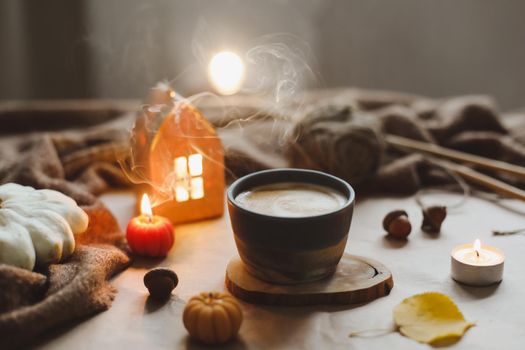 Autumn still life details in cozy home interior with a cup, candles, plaid. Hygge home decor. Halloween and Thanksgiving concept. Autumn banner