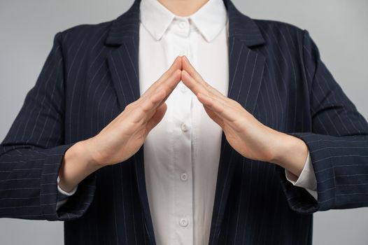 Business woman in a suit holding her hands in the shape of a house