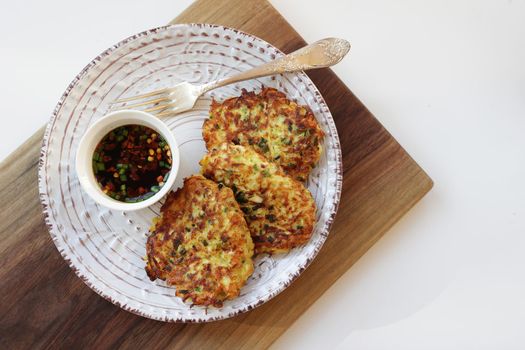 Zucchini fritters, vegetarian zucchini fritters on a white plate served with soy sauce in a small white bowl. Vegetarian food
