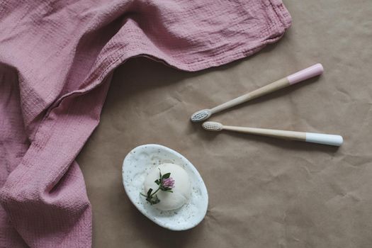 Soap bar or solid shampoo on a soap dish, bamboo toothbrush and towel top view with copyspace. Accessories for personal hygiene. Plastic free and eco friendly products in household.