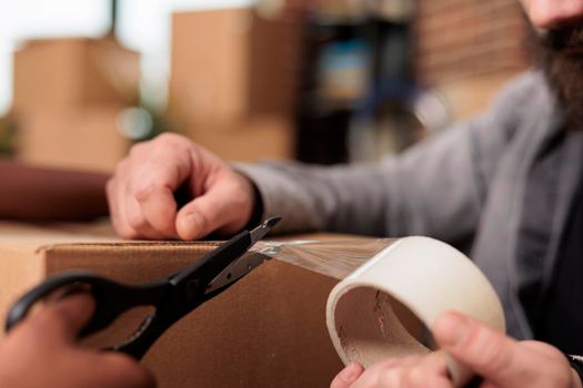 Married life partners using sticky tape scotch and scissors to pack furniture in boxes, moving in household property together. Packing things with adhesive roller to move in rented flat. Close up.