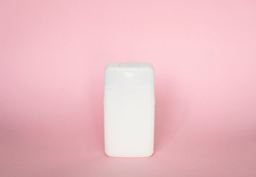 White plastic bottle of body care and beauty products. Studio photography of plastic bottle for shampoo, shower gel, creme isolated on pink background