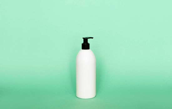 Liquid container for gel, lotion, cream, shampoo, bath foam. Cosmetic plastic bottle with dispenser pump on green background. Cosmetic packaging mockup with copy space