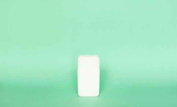 White plastic shampoo bottle isolated on green background. Skin care lotion. Bathing essential product. Shampoo bottle. Bath and body lotion. Fine liquid hand wash