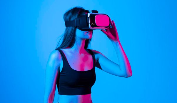 Young woman in a black t-shirt using the VR goggles and communicating with friends in a metaverse social network. Future technology concept