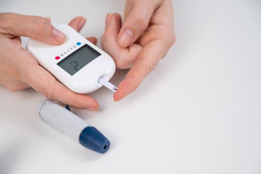 Woman measures blood sugar level with a glucometer