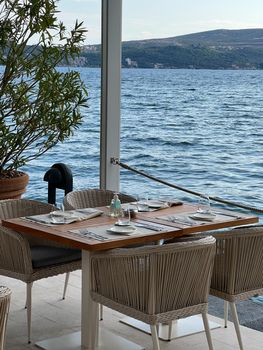 Wooden table with wicker chairs on the restaurant terrace by the sea. High quality photo
