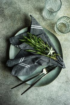 Minimalistic place setting with fresh rosemary herb on concrete table