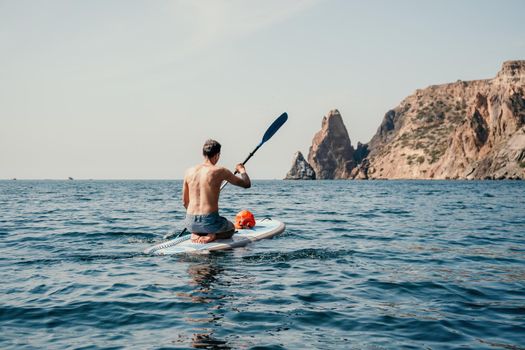 Side view foto of a man swiming and relaxing on the sup board. Sportive man in the sea on the Stand Up Paddle Board SUP. The concept of an active and healthy life in harmony with nature