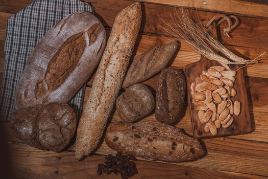 various types of artisan sourdough breads decorated with ears of wheat on a wooden table