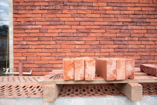 a new House is being built, the beginning of brickwork with red bricks, building materials, a pattern of stones, a natural background. High quality photo