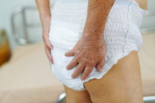 Asian elder senior woman patient wearing adult incontinence diaper pad in hospital.