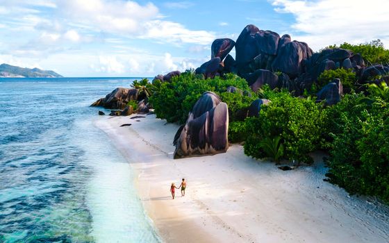 Anse Source d'Argent, La Digue Seychelles, a young couple of Caucasian men and Asian women on a tropical beach during a luxury vacation in Anse Source d'Argent, La Digue Seychelles